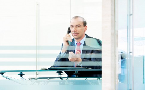 Firmenportraits---Mann-mit-Businesskleidung-telefoniert-am-Schreibtisch