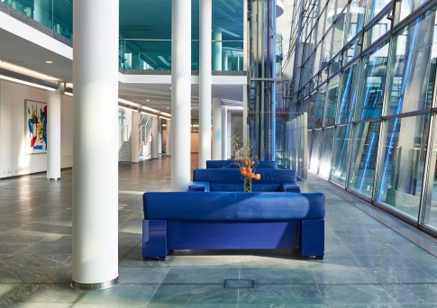 Architektur--Eingangshalle-eines-Bankgebaeudes-mit-blauen-Sofas-und-weissen-Saeulen